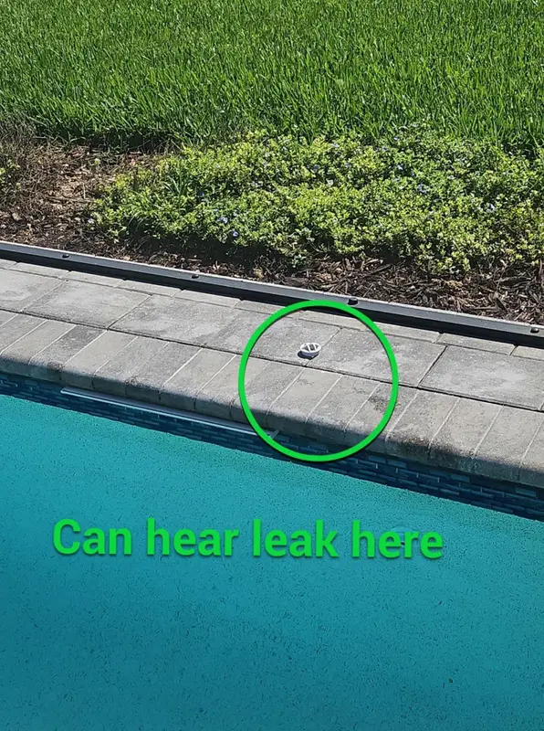 Pool deck edge with a green circle where the leak can be heard