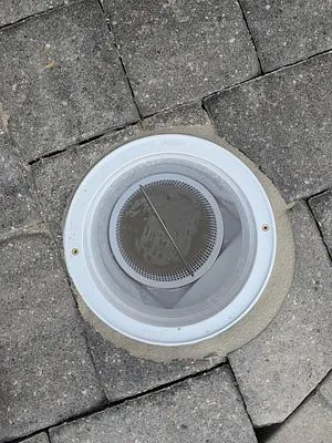 Finished pool skimmer with its basket in a paver deck