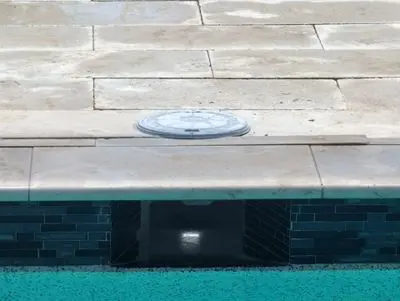New skimmer lid in a travertine pool deck