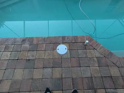 Skimmer lid in a reset paver deck