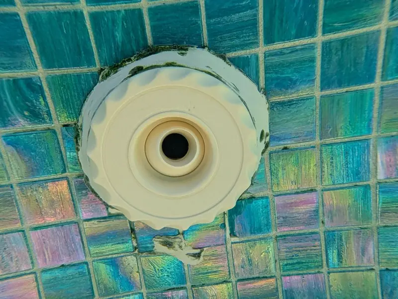 Spa jet fitting in glass tile with a leak around it