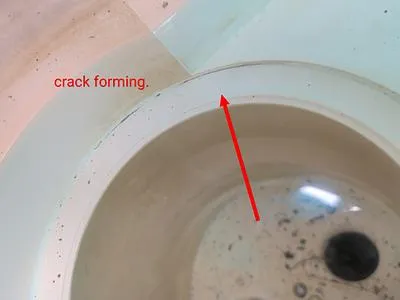 Inside of a pool skimmer with an arrow pointing to a crack forming