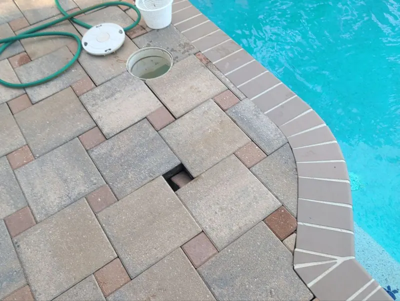 Paver pool deck with sinking pavers around the skimmer lid