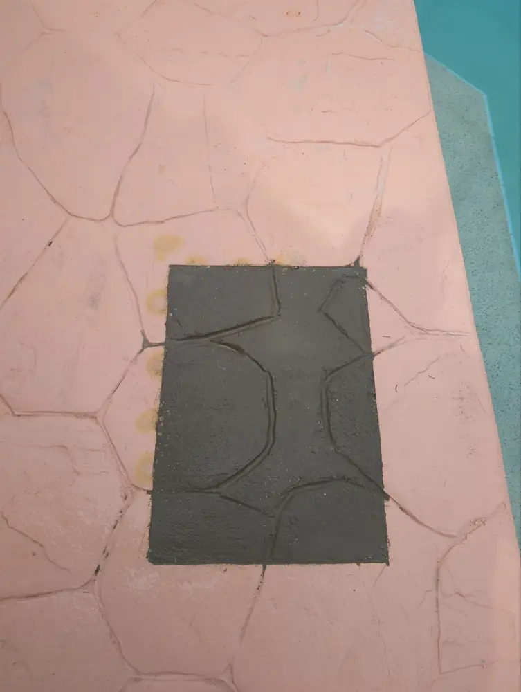 Finished concrete patch in a pool deck after a plumbing repair