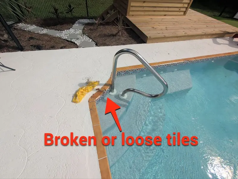 Pool coping by the ladder with an arrow pointing to loose tiles