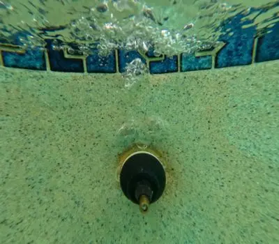 Pool return fitting underwater with water flowing out