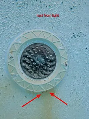 Pool light with arrows pointing to rust stains below it